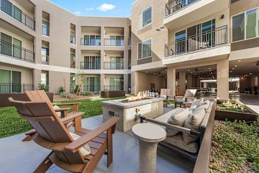 A patio area with a table, chairs and a grill.