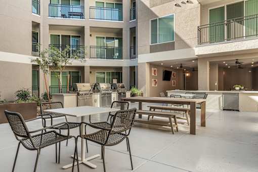 A patio with a table and chairs is surrounded by apartment buildings.