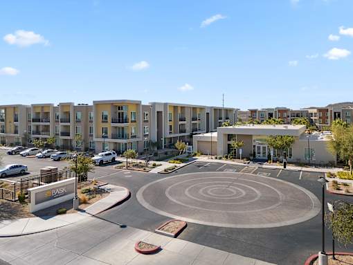 A roundabout in front of apartment buildings with cars parked on the side.