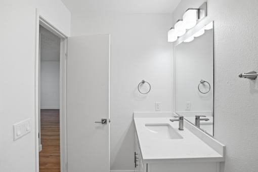 A white bathroom with a sink and mirror.