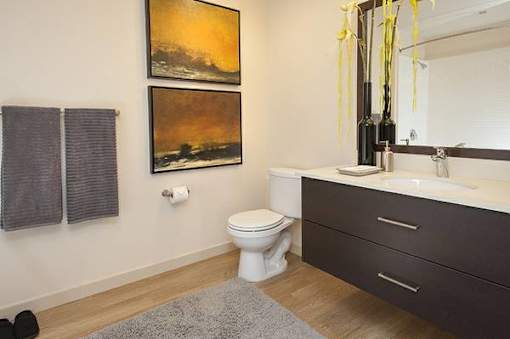 A bathroom with a toilet, sink, and two paintings on the wall.