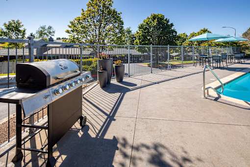 the clubhouse has a grill and a pool with umbrellas