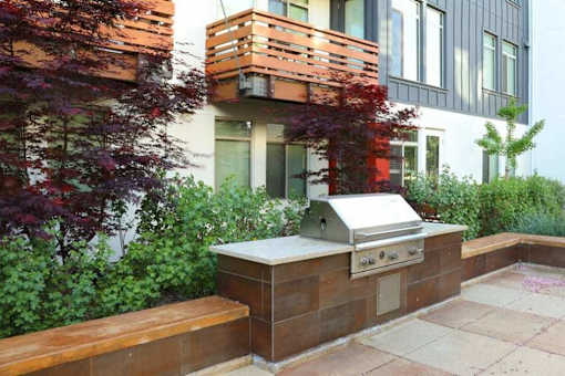 A modern outdoor kitchen with a grill and seating area.
