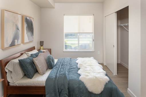 A bedroom with a bed, a window, and two paintings on the wall.