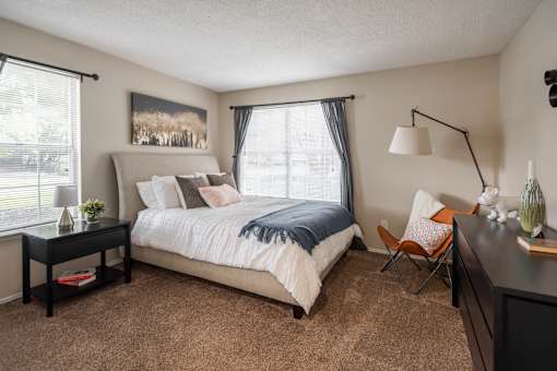 A bedroom with a large bed, a chair, and a painting on the wall.
