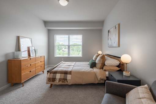 A bedroom with a bed, nightstand, and dresser.