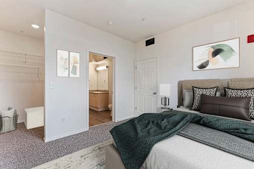 A bedroom with a bed, a couch, and a painting on the wall.