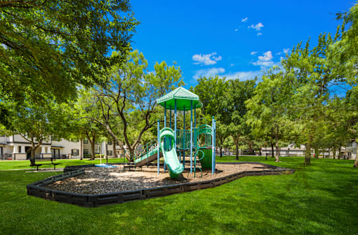 A playground with a green slide and a green roofed structure.