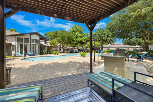 A wooden deck with a bench overlooks a pool.