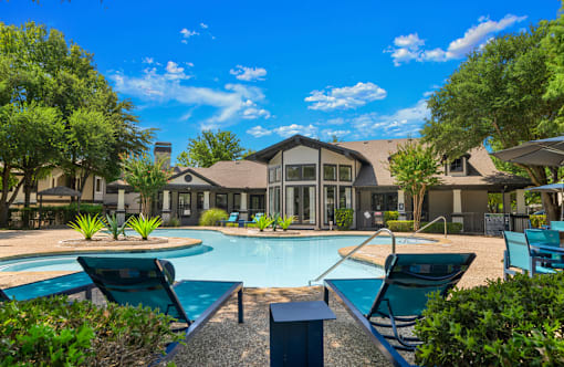 A pool area with lounge chairs and a building in the background.