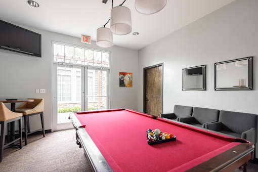 A pool table is in the middle of a room with a couch and chairs.