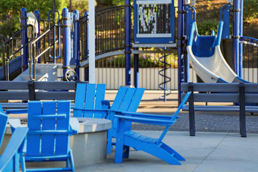 A playground with blue chairs and a slide.