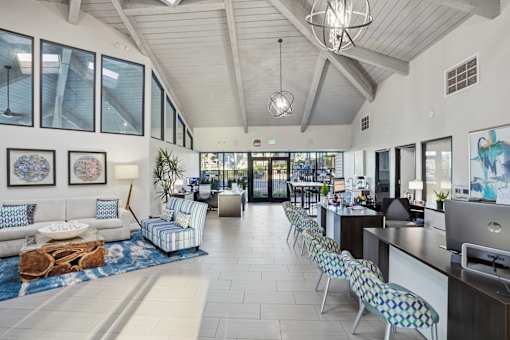 A spacious office space with a long white couch and a blue patterned chair.
