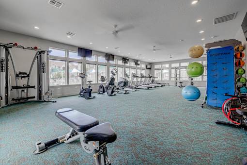 A gym with a variety of equipment including a bench press, a leg press, and a rowing machine.