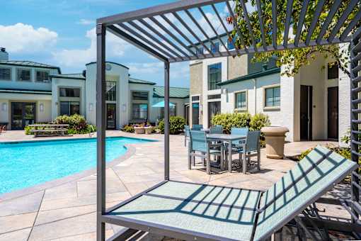 A patio with a table and chairs under a pergola.