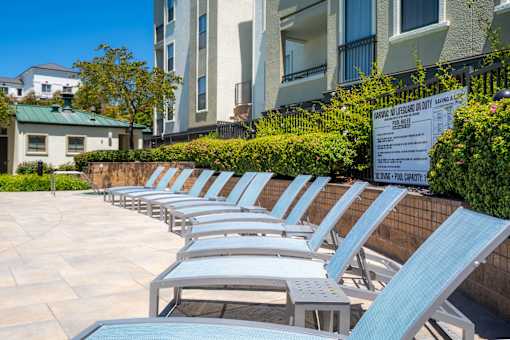 A row of sun loungers are arranged on a patio.