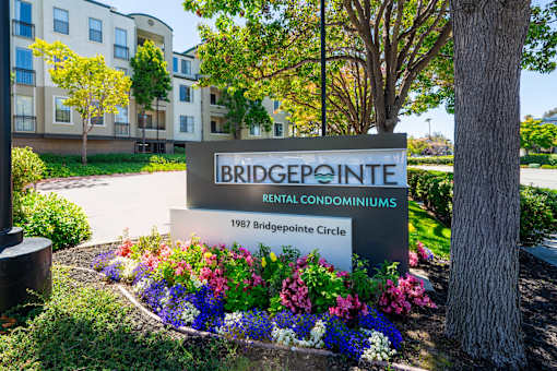 A sign for Bridgepointe Rental Condominiums stands in front of a building.