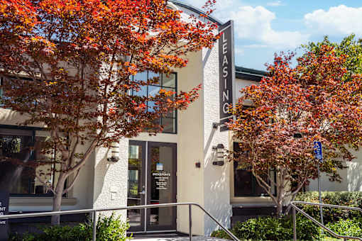 A leasing office building with trees in front.