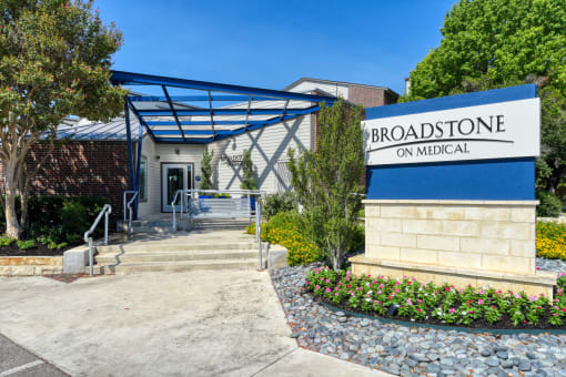 a white building with a blue awning and a sign that reads broadstone on m