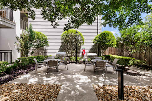 A patio with a table and chairs surrounded by a gravel area and trees.