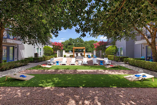 A playground area with a slide and swings surrounded by trees and houses.