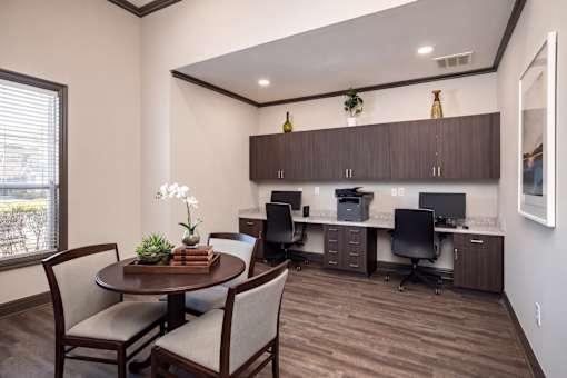 A room with a table, chairs, and a cabinet with a computer setup.