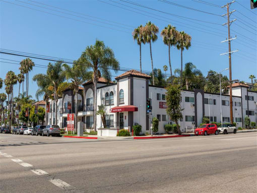 a row of apartment buildings with palm trees in the background at Pacific Rose, Los Angeles, CA 90034