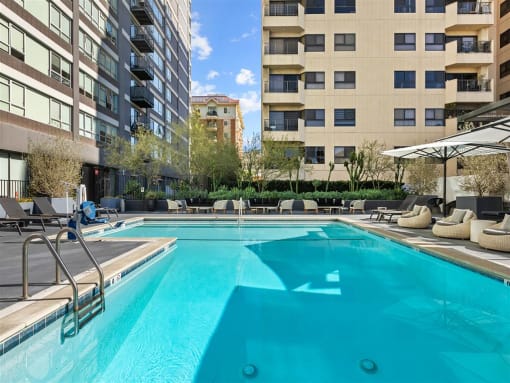 a swimming pool with chairs and umbrellas in front of a building at The View, California, 90005