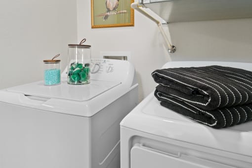 a white washer and dryer in a bathroom with a stack of black towels