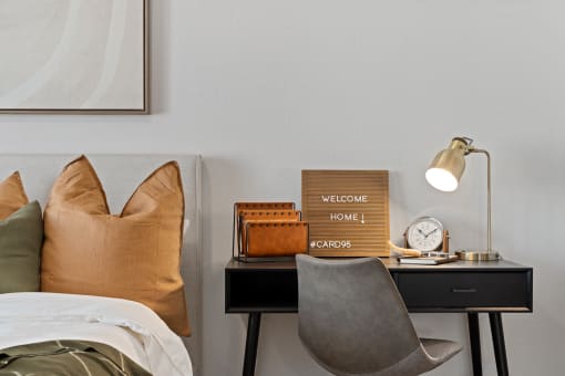 a bedroom with a bed and a desk with a clock and a sign on it
