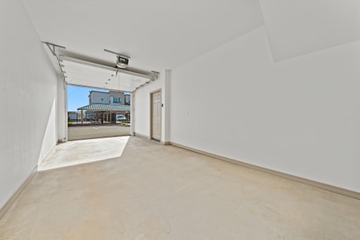 a spacious living room with white walls and a door to a parking garage