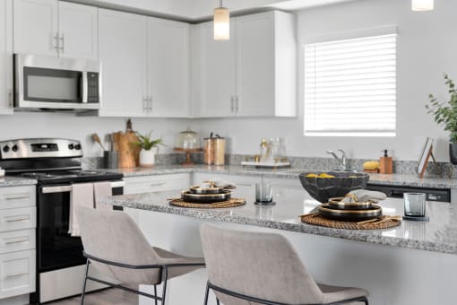 a kitchen with white cabinets and granite counter tops and a table with chairs