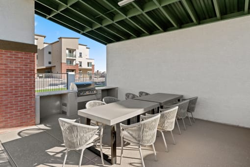 a patio with a table and chairs and a grill