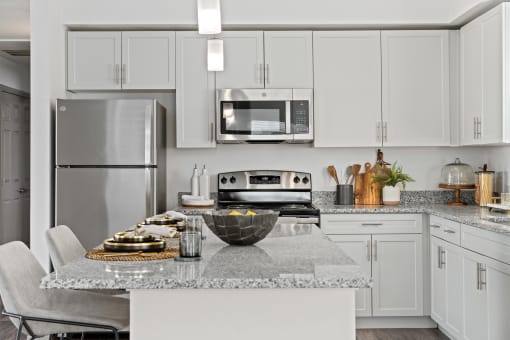 a kitchen with white cabinets and a marble counter top