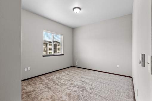 A room with a carpeted floor and a window showing a building outside.