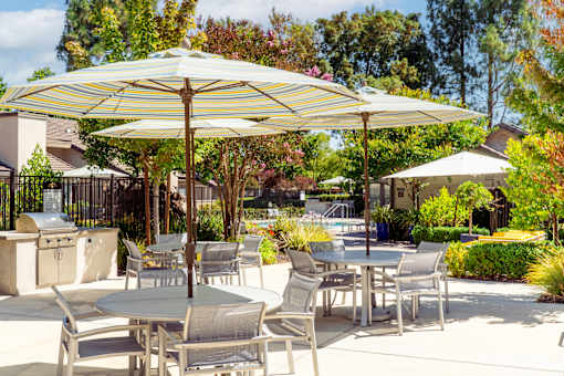 A patio with a table and chairs under a striped umbrella.