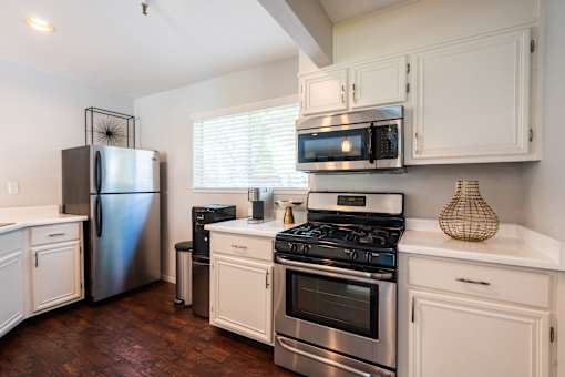 A kitchen with a stainless steel refrigerator, oven, and microwave.