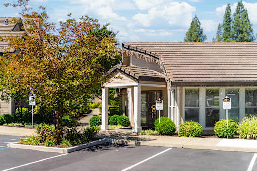 A building with a brown roof and a parking lot in front.