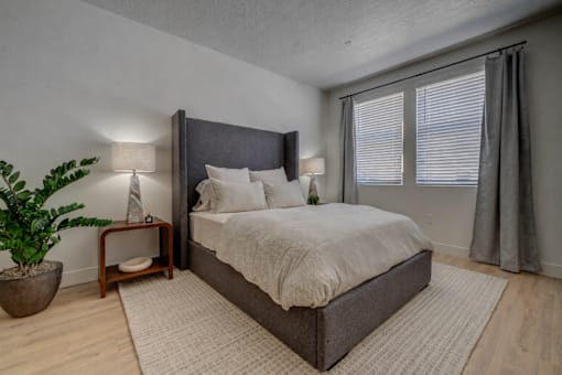 A bedroom with a large bed, a potted plant, and two lamps.