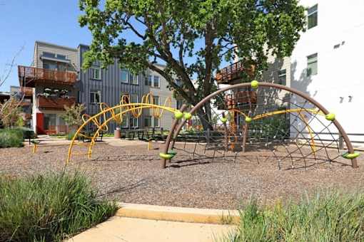 A playground with a yellow and green swing set.