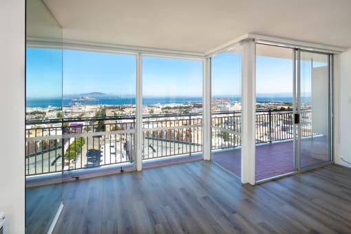 an open living room with hardwood floors and a balcony with a view of the city