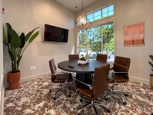 a conference room with a round table and chairs and a television