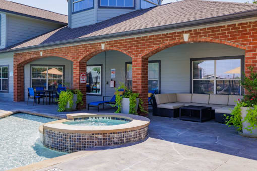 a covered patio with a hot tub and a seating area