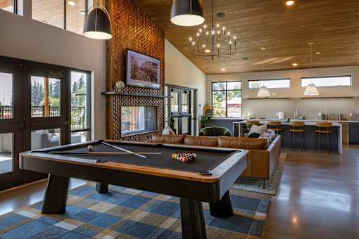 A pool table is in the middle of a room with a couch and a bar.