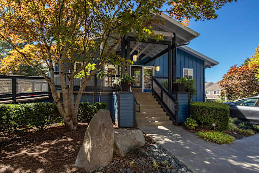 A blue house with a large rock in front of it.
