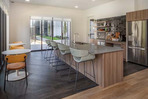 A modern kitchen with a wooden island and grey chairs at The Arvon, Vancouver, WA