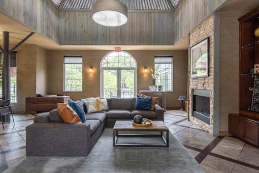 A large grey couch with orange and blue pillows sits in a spacious living room.