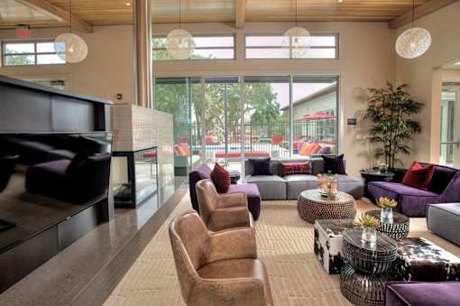A living room with a purple couch and a wooden chair.