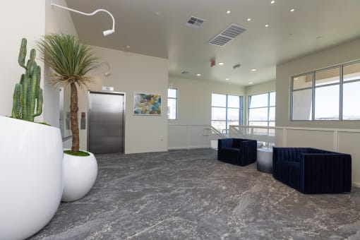 a lobby with two blue couches and a cactus in a white vase at Element 12 Apartments, Henderson NV