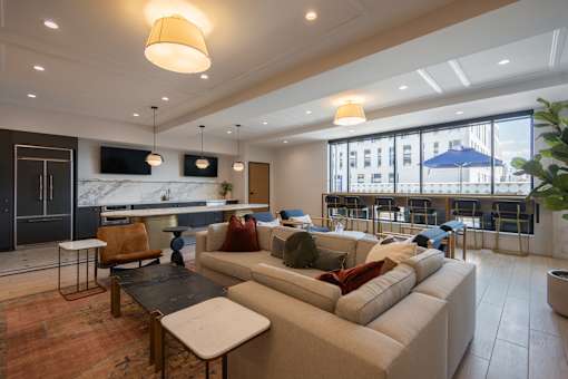 A modern living room with a large couch and a kitchen area in the background.